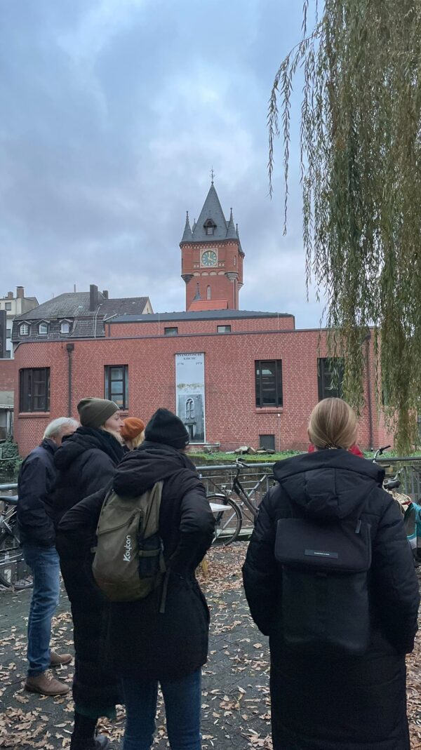 Eine Gruppe Personen steht bei einer Stadtführung an der Rückseite des ehemaligen Rathausturmes.