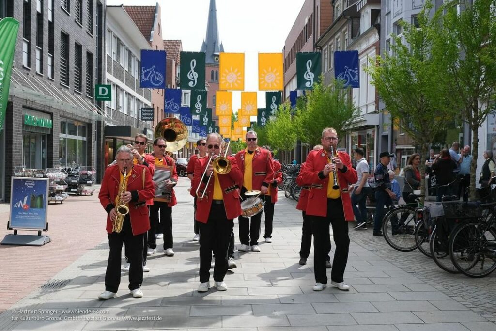 Eine Brassband, bestehend aus 10 Personen, läuft mit ihren Instrumenten am Jazzfest-Wochenende durch die geschmückte Innenstadt.