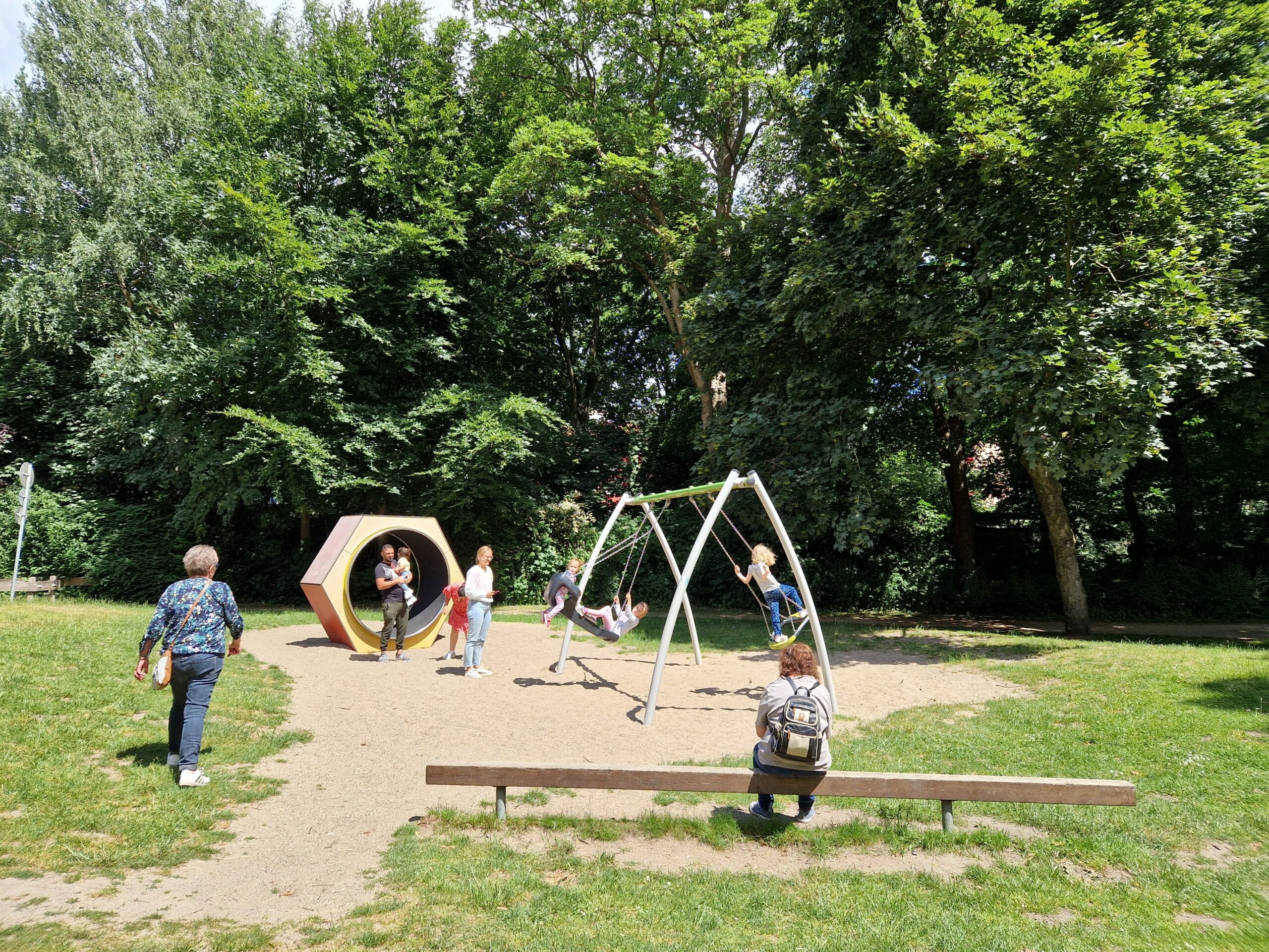 Auf dem Bild ist der Spielplatz im Stadtpark Gronau zu sehen. Es spielen Kinder auf den Spielgeräten.