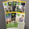 7 Radwanderflyer liegen aufgefächert auf einer dunklen Unterlage. Dabei liegt ein Hinweis zur entsprechenden Beschilderung.