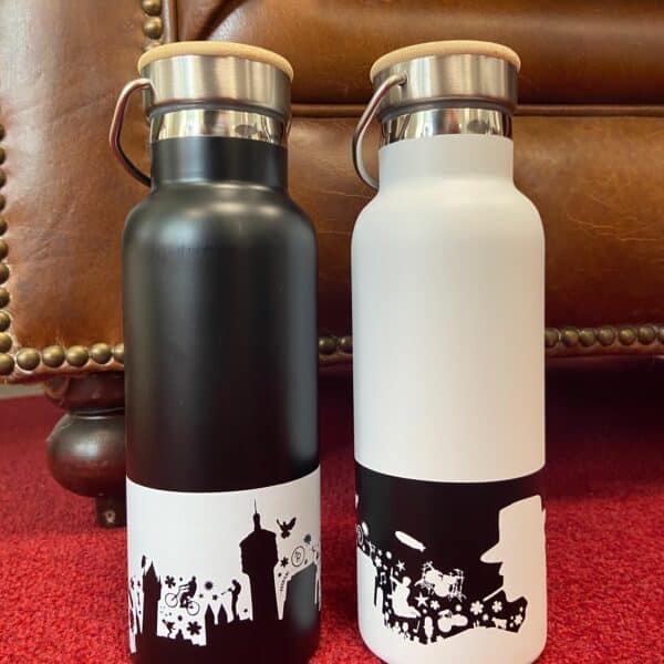 A black Gronau drinking bottle with a white motif and a white Gronau drinking bottle with a black motif next to each other on a red background.