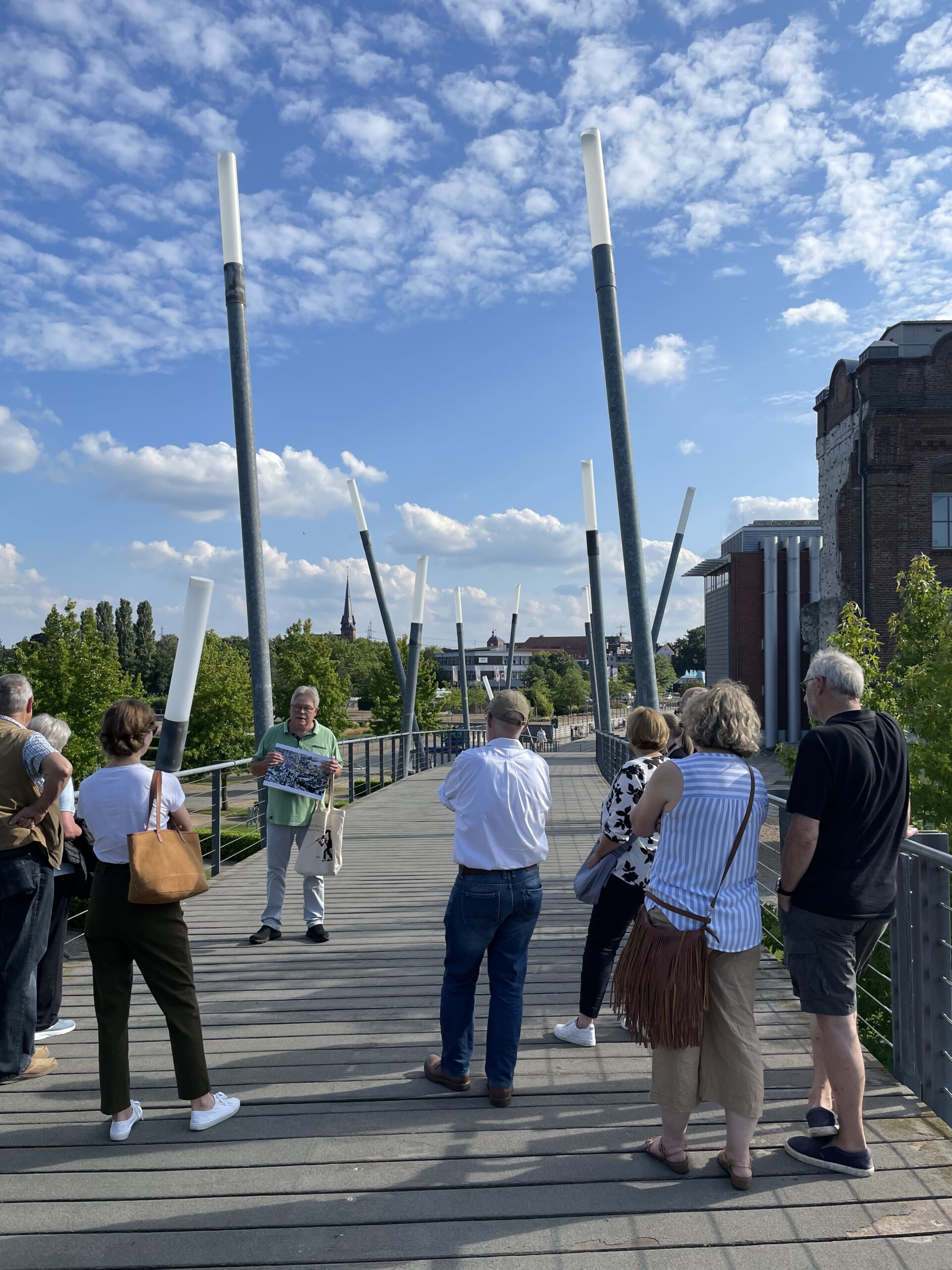 Der Stadtführer im Hintergrund mit Teilnehmern im Vordergrund auf der Bogenbrücke in Gronau