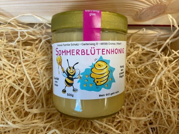 Ein Glas Honig von der Imkerei Schatz in Gronau mit der Aufschrift "Sommerblütenhonig". Auf dem Etikett ist eine Biene und ein Bienenstock zu sehen.