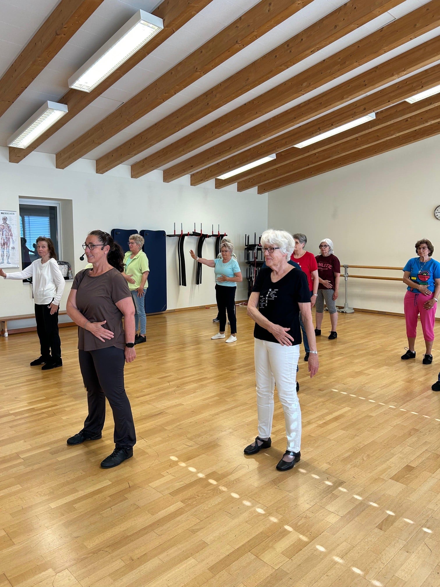 Op de foto zie je een groep mensen die naast elkaar dansen.