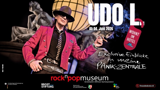 Das rock'n'popmuseum lädt zur neuen Sonderausstellung "Udo L wohnt im Hotel ein". Auf dem Plakat ist Udo Lindenberg zu sehen, der eine Zigarre im Mund hat. Seine andere Hand liegt an seinem Gürtel.
