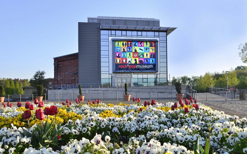 Op de foto is het rock-'n'-popmuseum te zien, met een bloemenweide erachter.